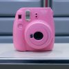 Close-up of a pink instant camera on a metal table, indoors.